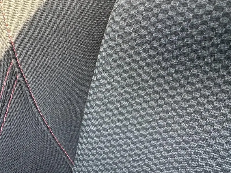 Détail du tissu de siège avec motif à damier gris et coutures rouges sur Ford Puma 2024 ST-Line.