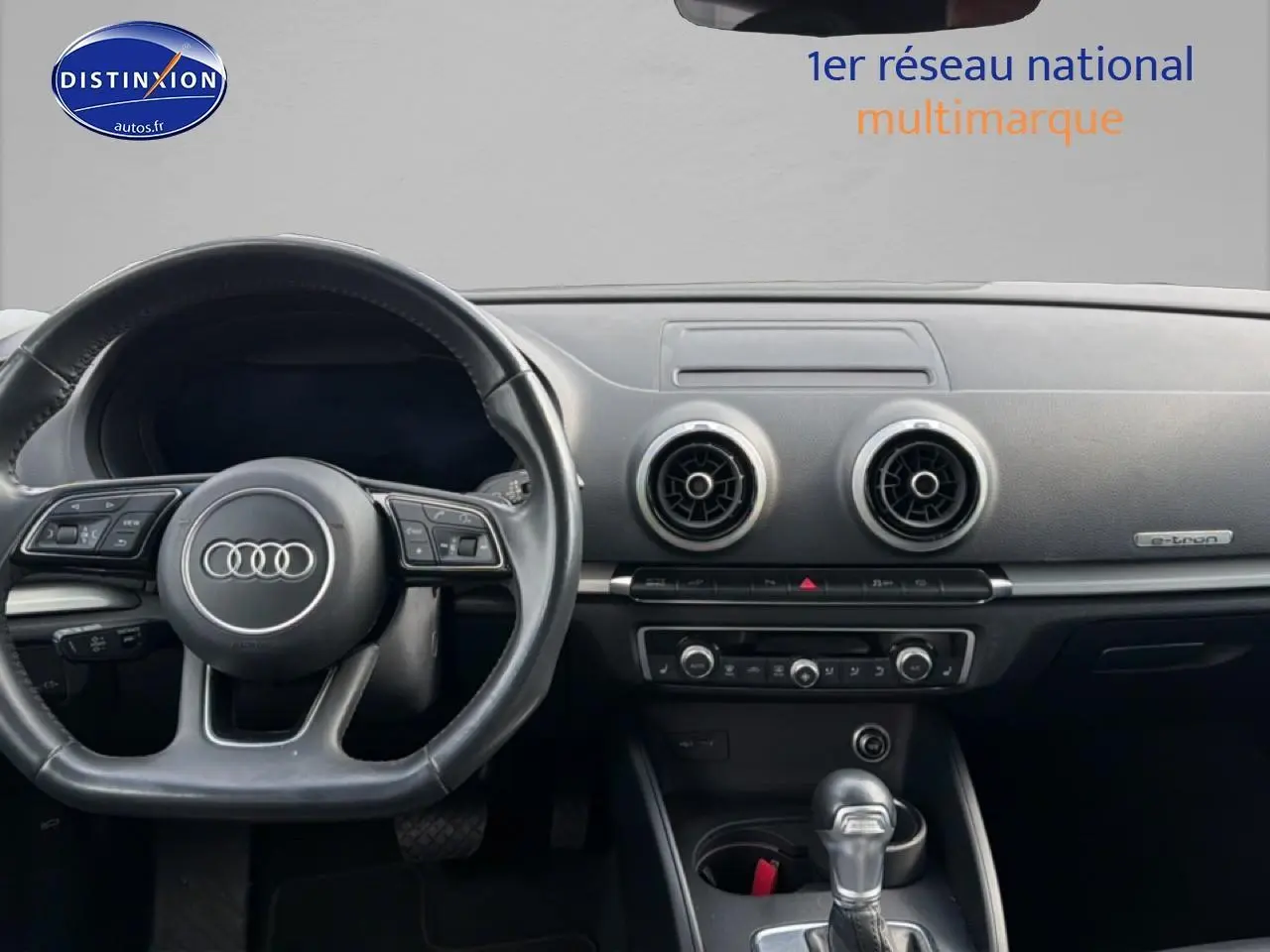 Vue intérieure du tableau de bord et volant noir d'une Audi A3 Sportback 40 e-tron, avec aérateurs ronds et badge e-tron.