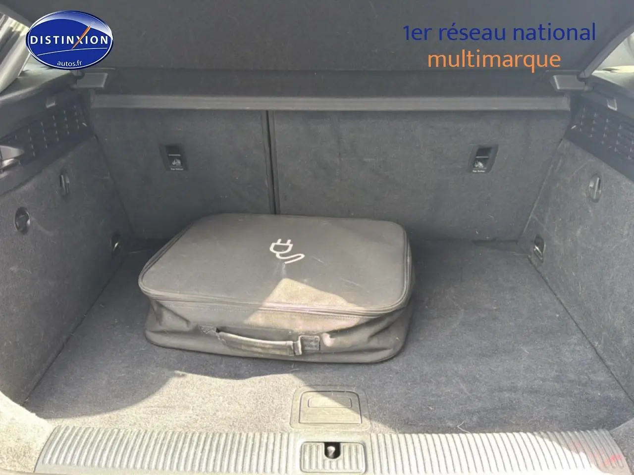 Coffre ouvert d’Audi A3 Sportback noir 2020 avec sac de chargeur hybride posé au centre.