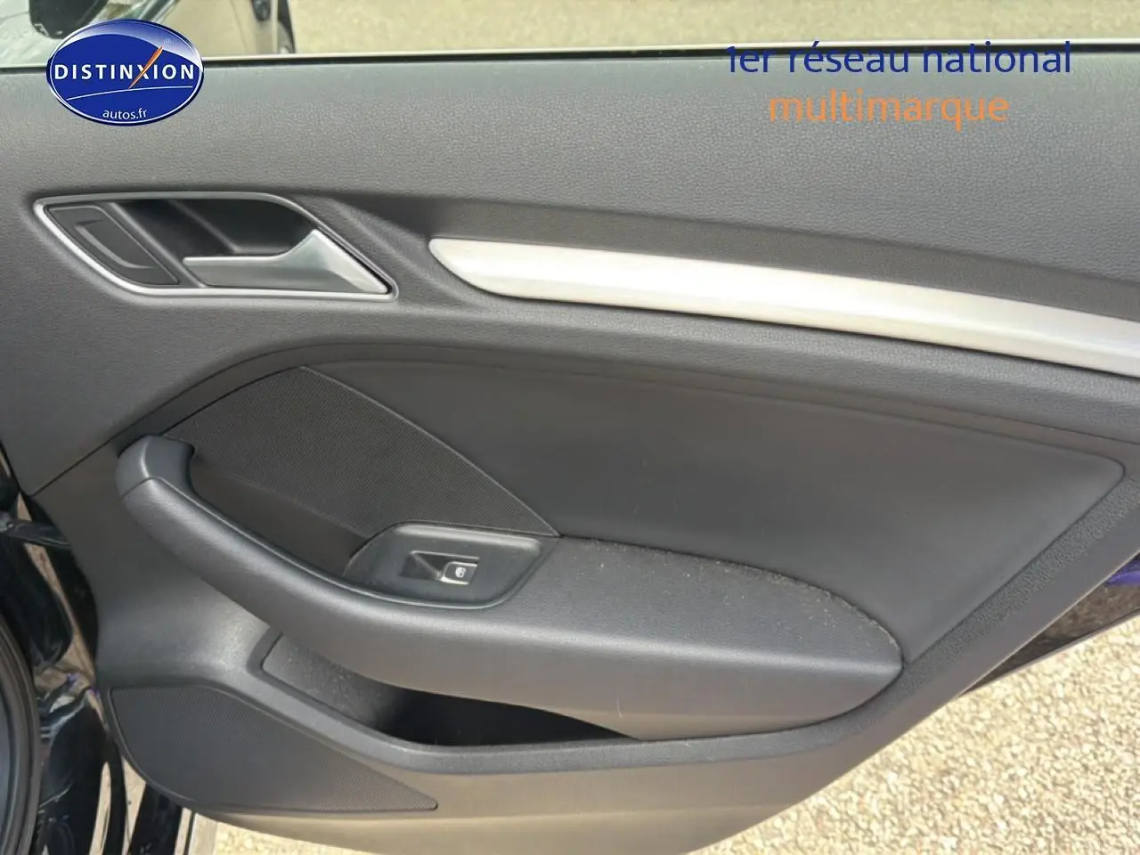 Vue intérieure du panneau de porte côté gauche noir de l'Audi A3 Sportback 40 e-tron avec poignée et commande de fenêtre électrique.