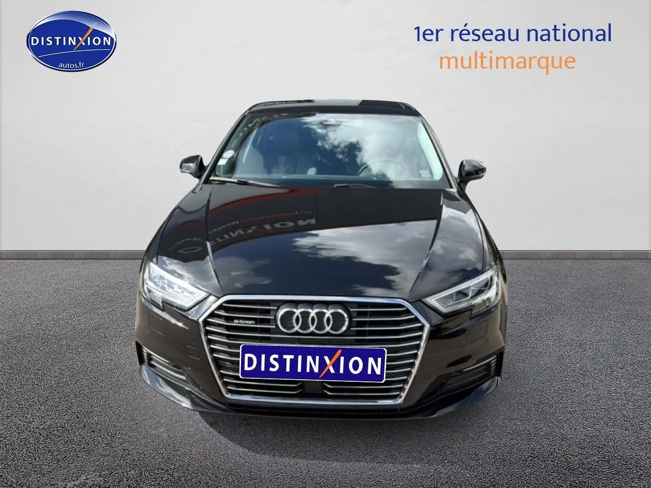 Vue avant d'une Audi A3 Sportback noire avec calandre chromée et phares LED, stationnée sur sol gris.