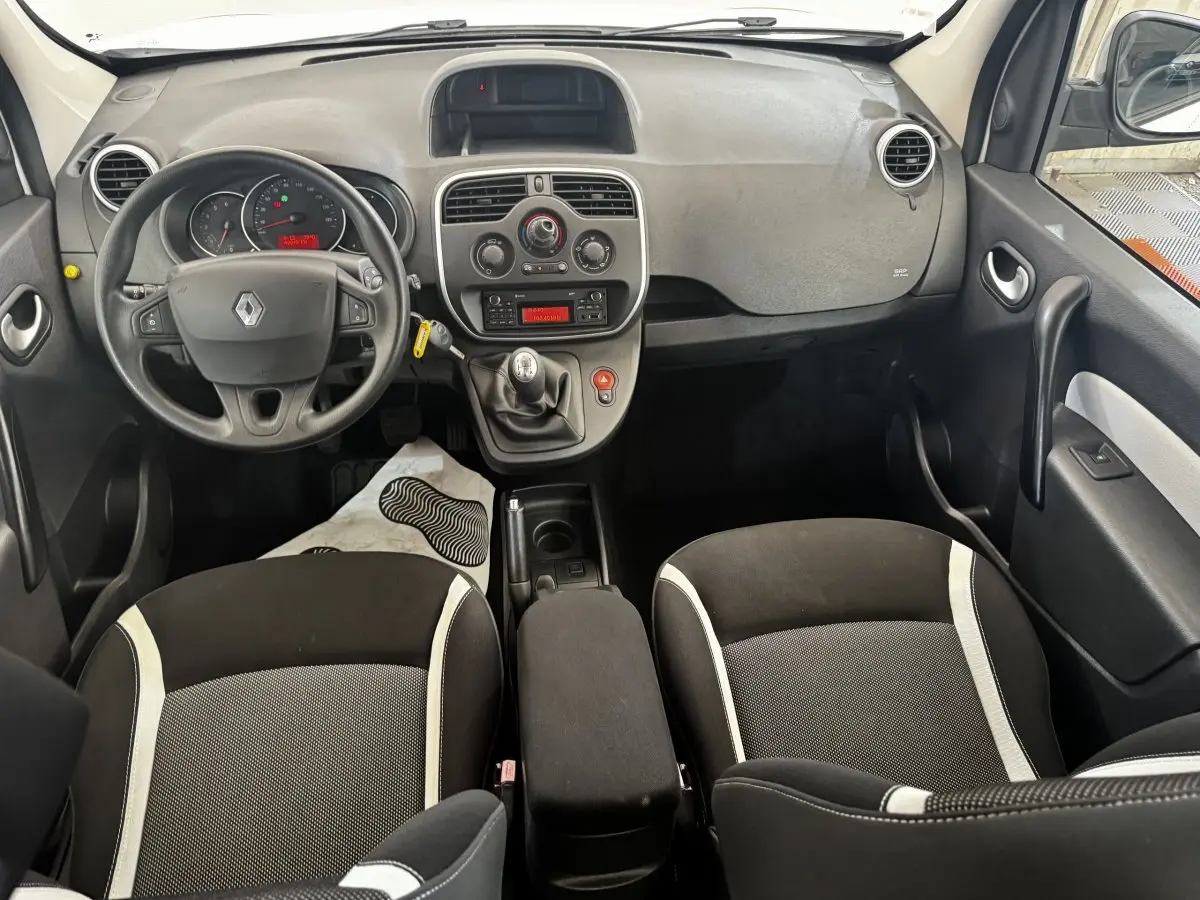 Vue intérieure avant du Renault Kangoo 2016 avec tableau de bord gris, volant multifonctions et sièges noirs à bandes claires.