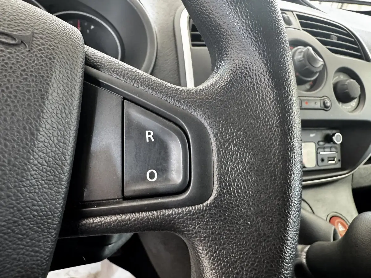Gros plan sur le volant multifonctions noir du Renault Kangoo 2016, avec tableau de bord et commandes visibles en arrière-plan.