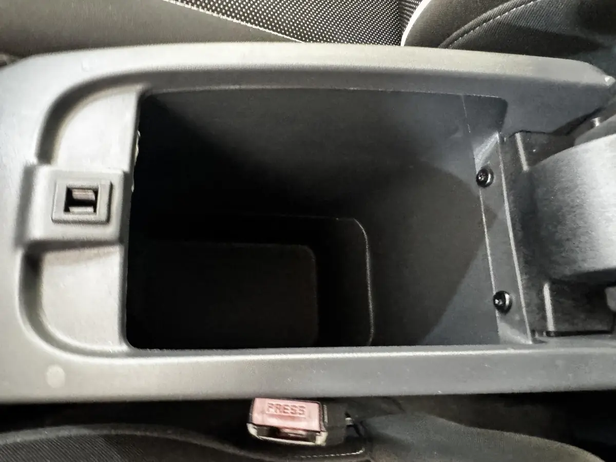 Gros plan sur le rangement central ouvert de l’habitacle du Renault Kangoo blanc, montrant le compartiment vide.