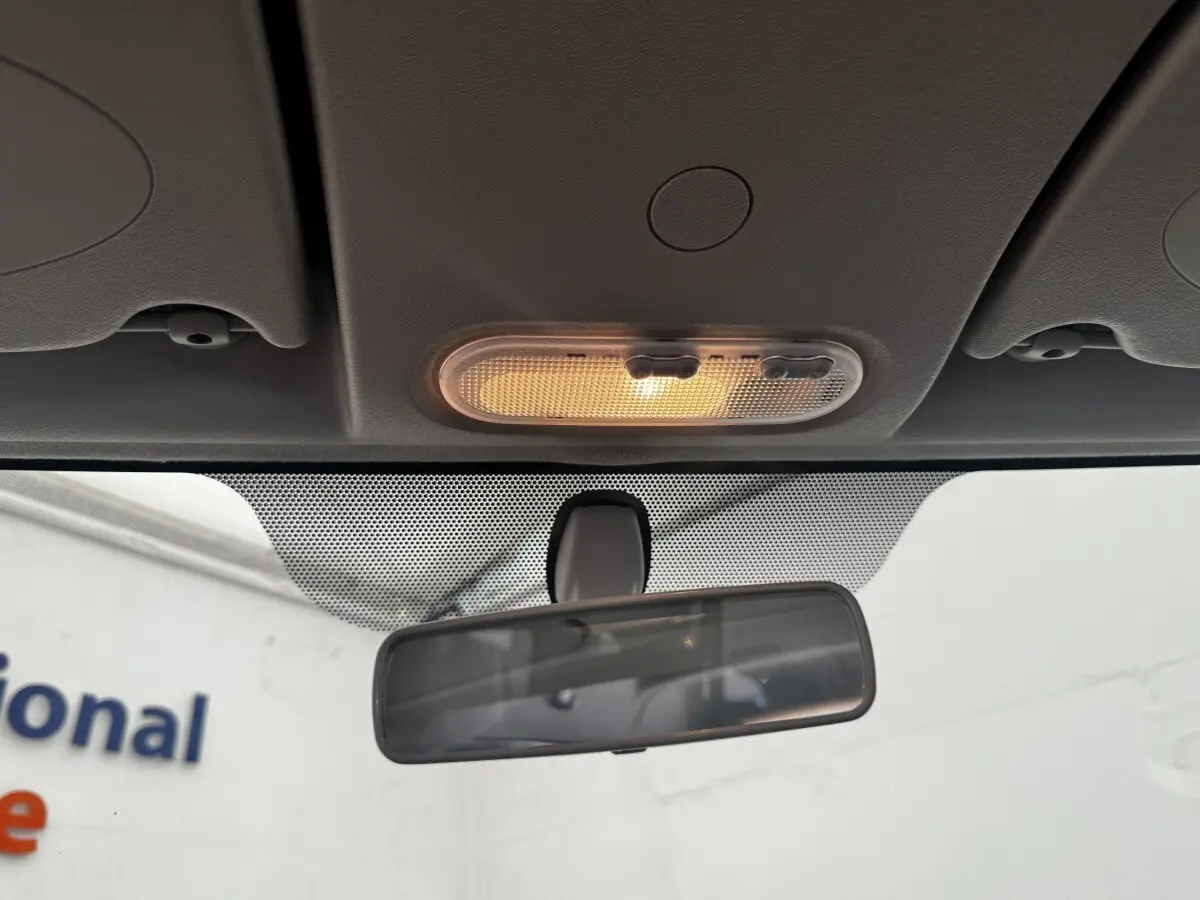 Vue intérieure centrée sur le plafonnier allumé et le rétroviseur intérieur du Renault Kangoo blanc de 2016.