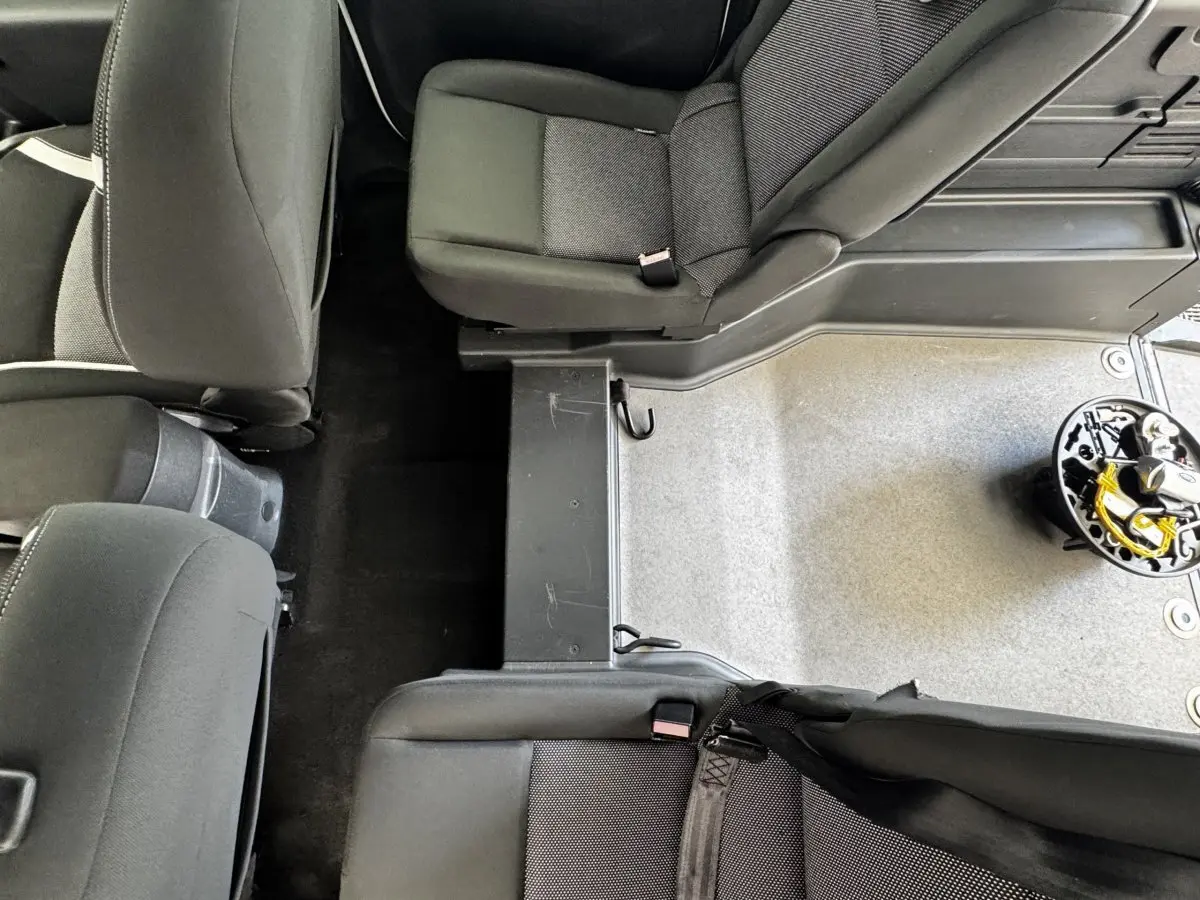 Vue plongeante sur l’intérieur arrière du Renault Kangoo 2016, sièges noirs et plancher partiellement découvert.