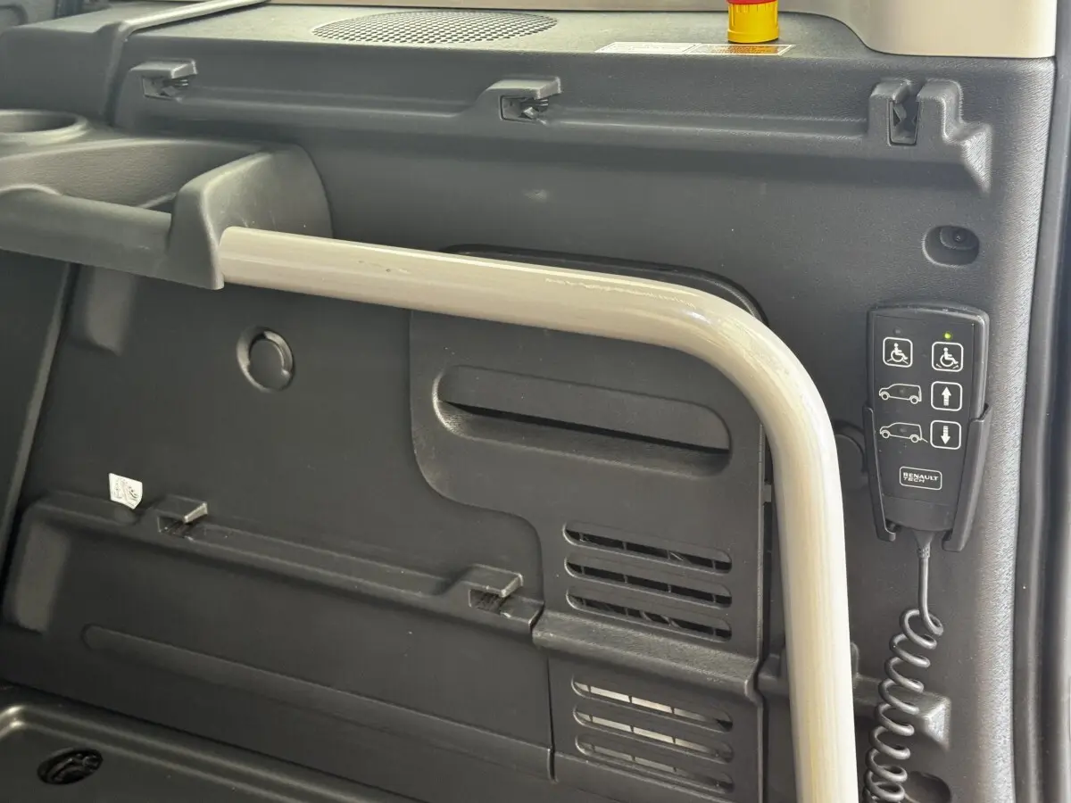 Détail intérieur montrant la commande d’accessibilité et la poignée de maintien dans un Renault Kangoo blanc 2016.