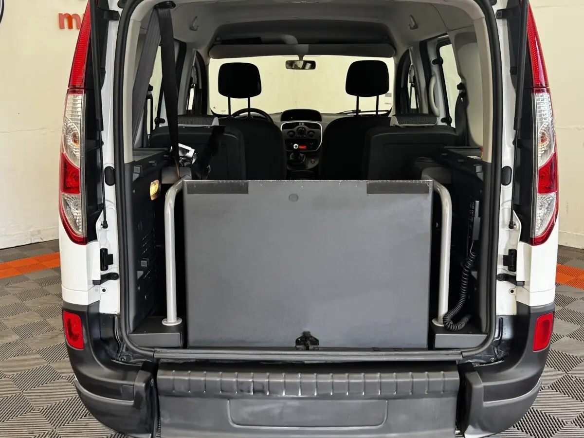 Vue arrière ouverte du Renault Kangoo blanc 2016, montrant l'intérieur et une barrière de sécurité grise dans le coffre.