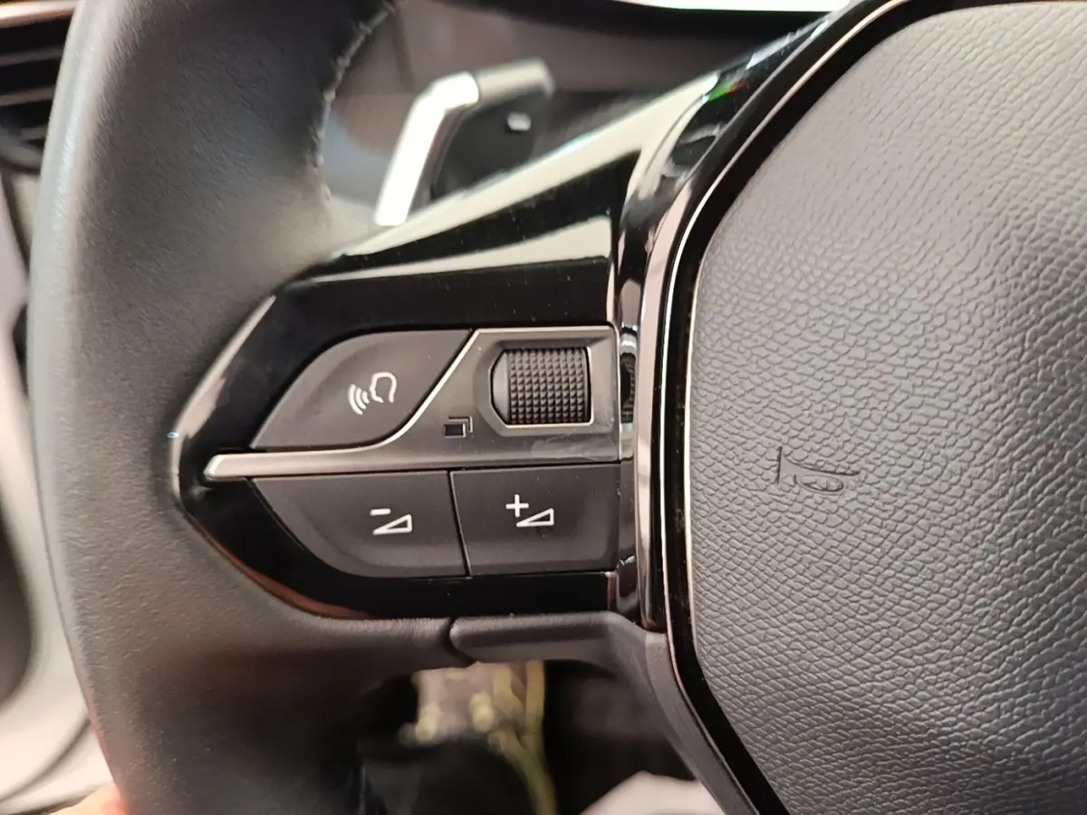 Gros plan sur le volant cuir noir de la Peugeot 2008 2021 avec commandes vocales et réglage du volume.