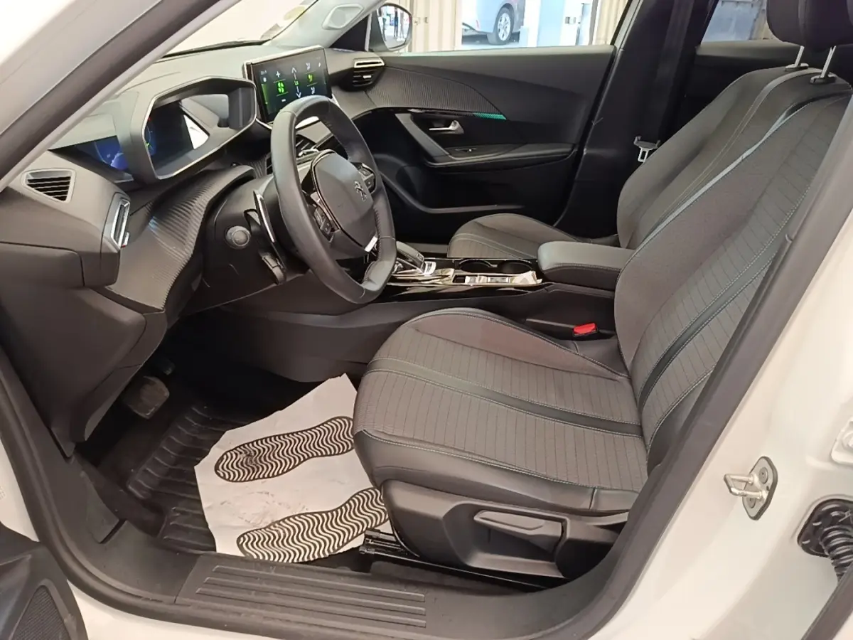 Vue intérieure côté conducteur du Peugeot 2008 blanc, avec sièges gris, volant cuir multifonctions et écran tactile.