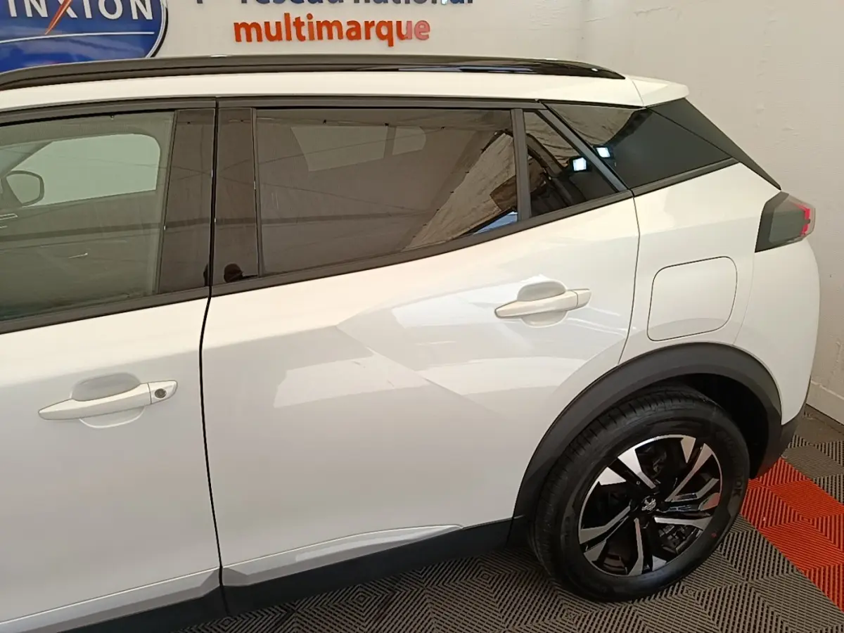 Vue latérale droite d'un Peugeot 2008 blanc avec jantes alliage noires et vitres teintées.