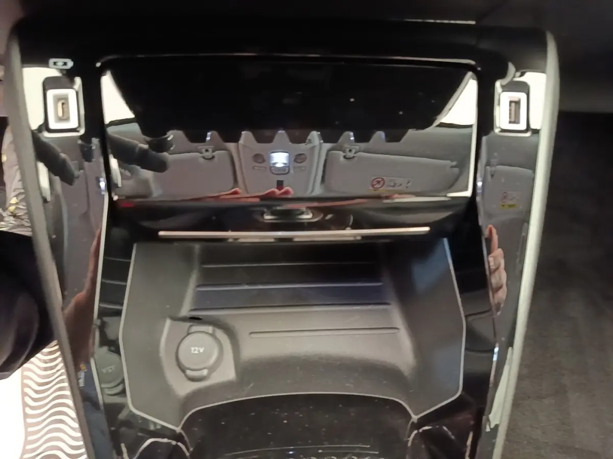 Gros plan sur la console centrale noire du Peugeot 2008 blanc, avec prise 12V visible et finition brillante.