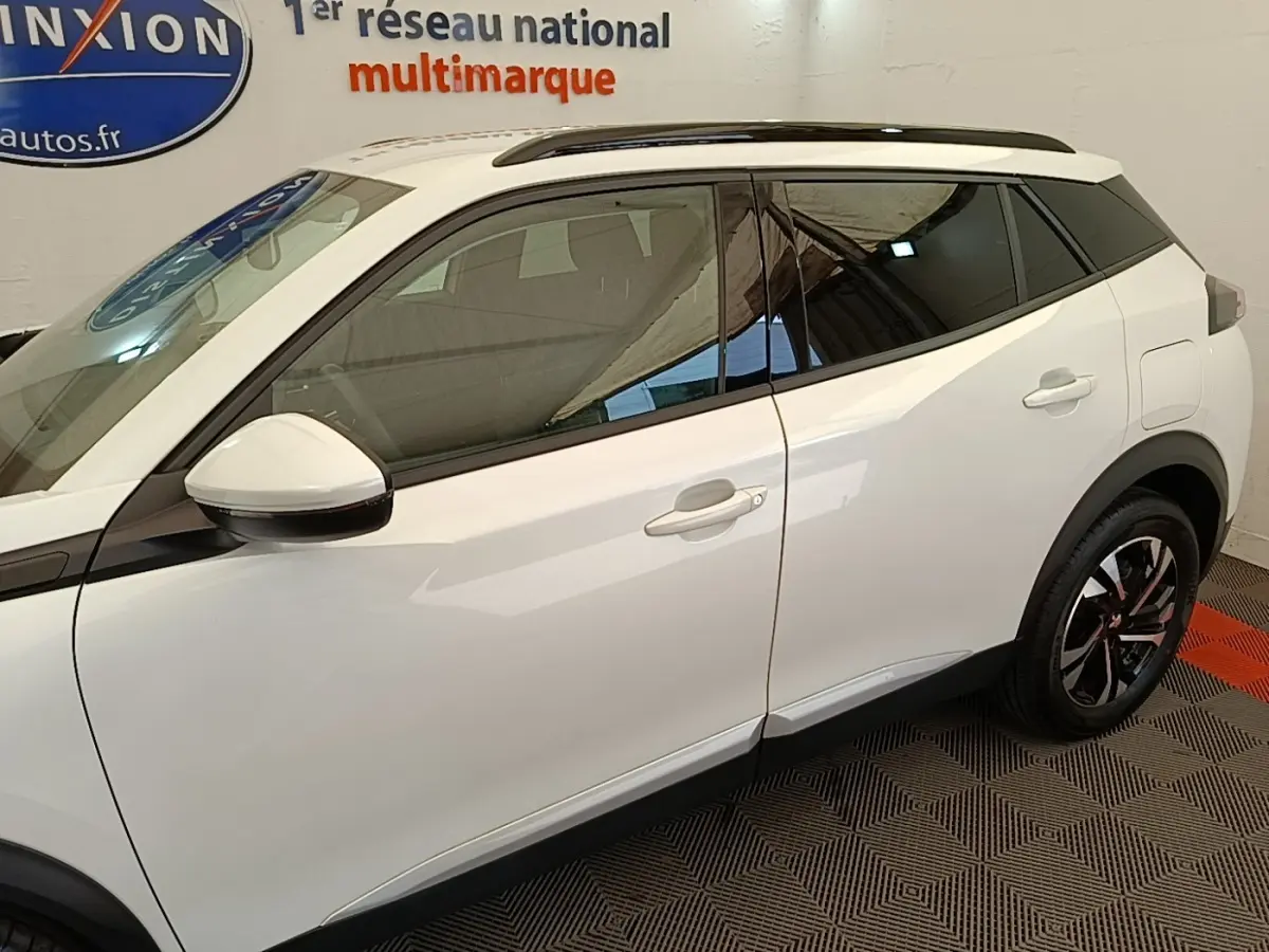 Vue latérale droite du Peugeot 2008 blanc de 2021 avec vitres teintées et jantes alliage noires et argentées.