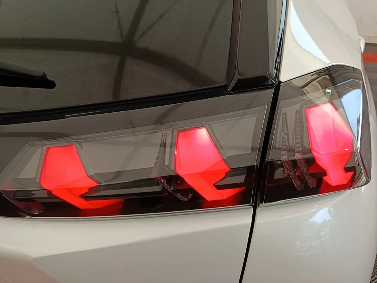Gros plan sur les feux arrière rouges du Peugeot 2008 blanc, vue du côté droit arrière du véhicule.