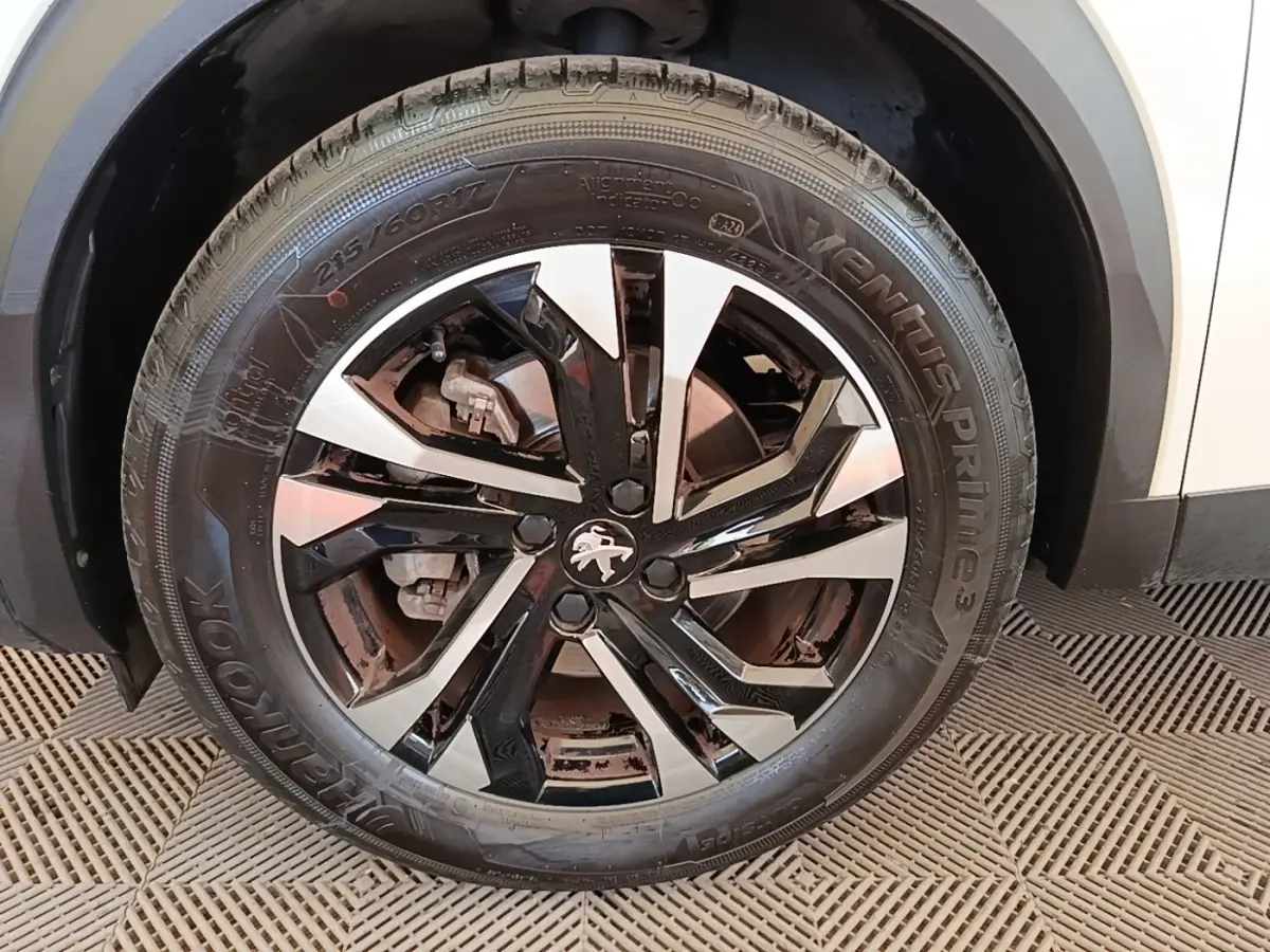 Gros plan sur la roue avant gauche blanche d’un Peugeot 2008 avec jante alliage noire et argentée.