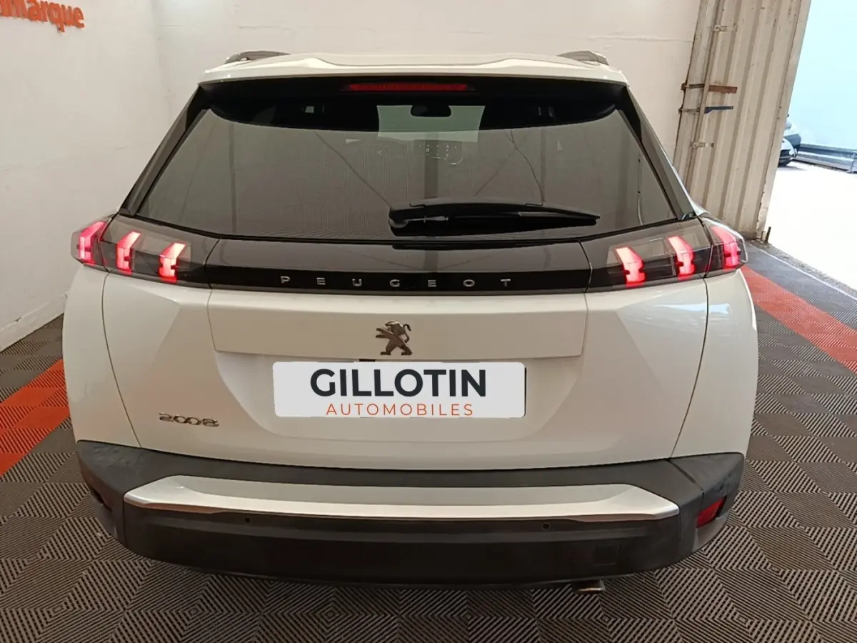 Vue arrière d'un Peugeot 2008 blanc avec feux LED distinctifs et logo lion sur hayon noir brillant.
