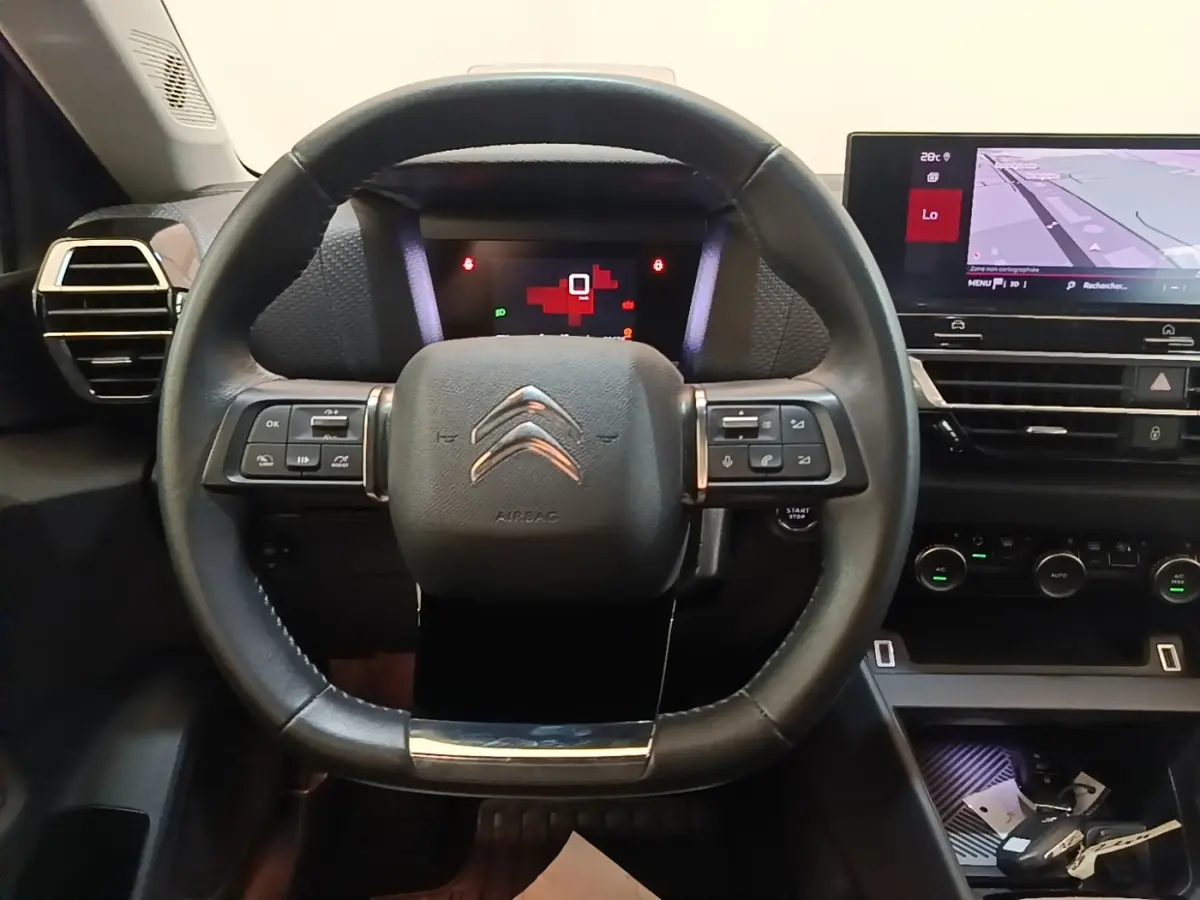 Vue intérieure centrée sur le volant cuir multifonctions de la Citroën C4 avec écran tactile de navigation visible.