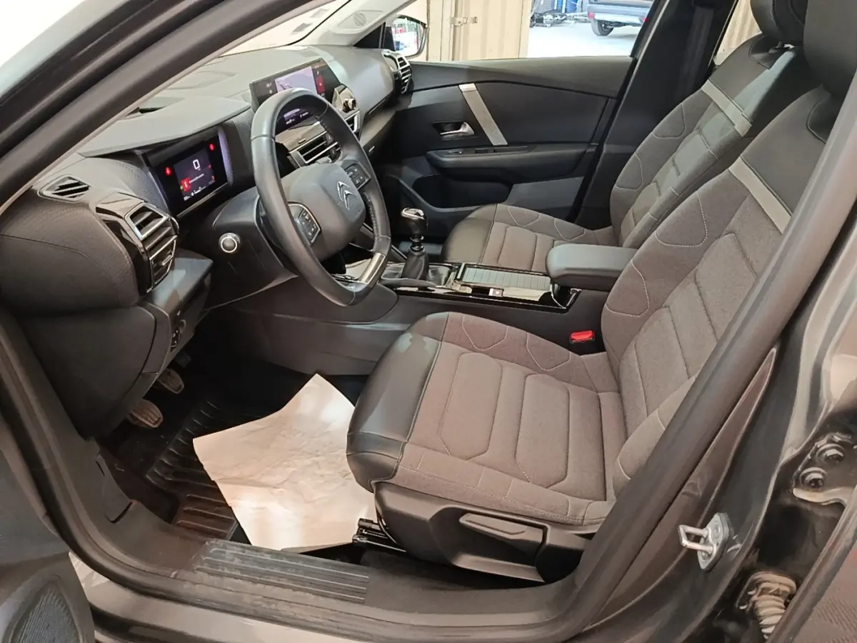 Vue intérieure côté conducteur de la Citroën C4 gris clair 2021, avec sièges tissu et cuir et tableau de bord digital.