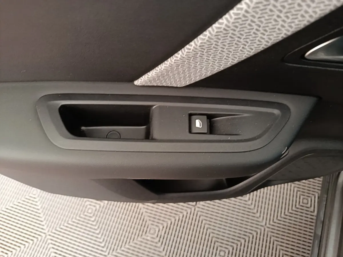 Gros plan sur la poignée intérieure de porte côté droit d’une Citroën C4 gris clair, avec bouton de verrouillage.