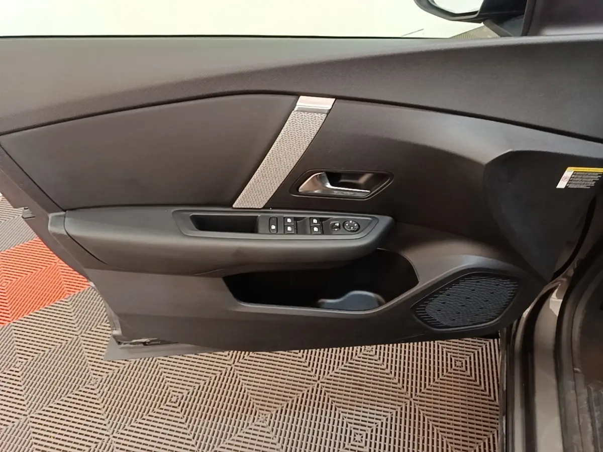 Vue intérieure du panneau de porte avant gauche gris foncé de la Citroën C4 avec commandes de vitres et haut-parleur intégré.