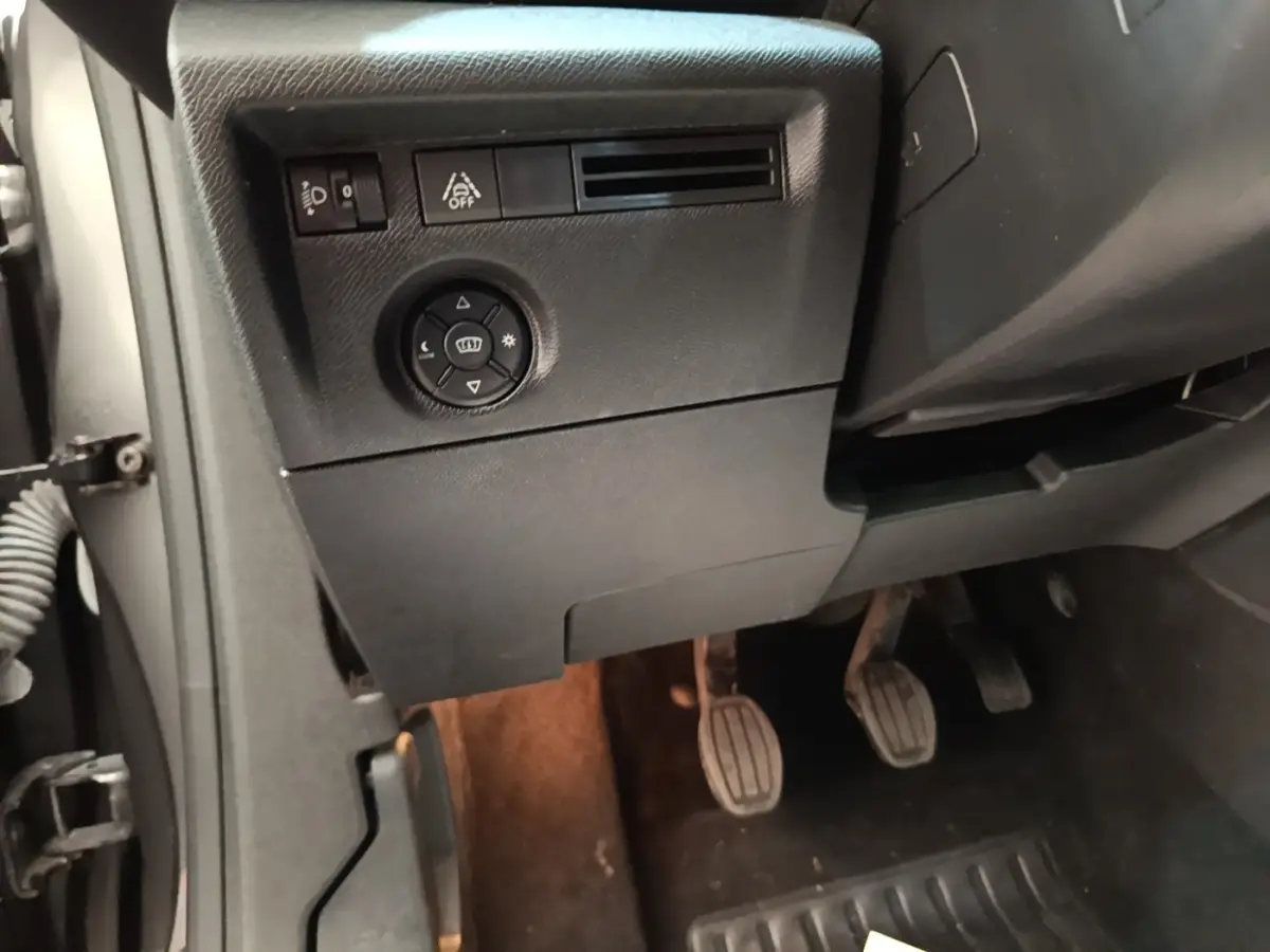 Vue intérieure côté conducteur de la Citroën C4 2021, montrant les pédales et commandes de réglage des phares.