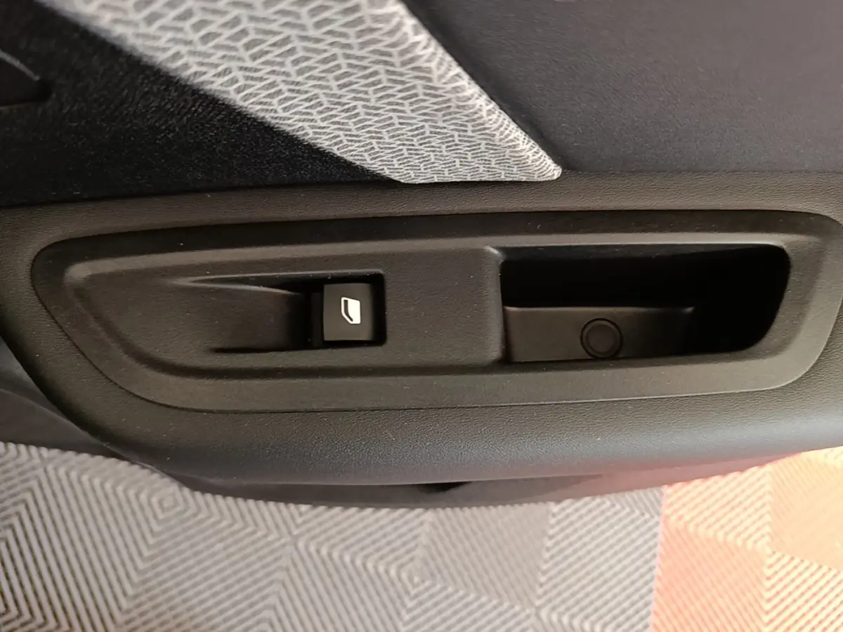 Gros plan sur la commande de lève-vitre électrique côté porte arrière d’une Citroën C4 gris clair.