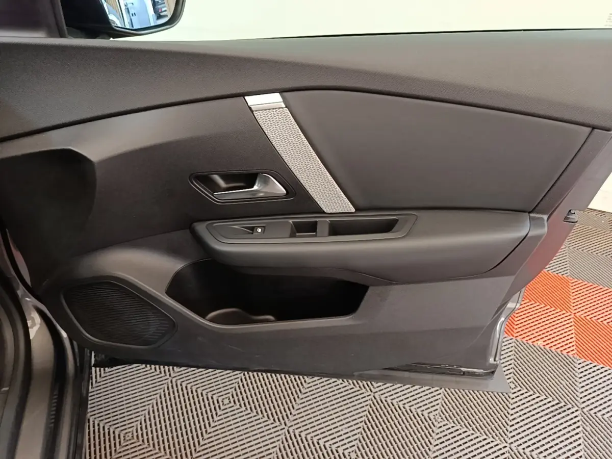 Vue intérieure côté gauche de la porte avant d'une Citroën C4 gris clair avec garniture noire et insert décoratif argenté.