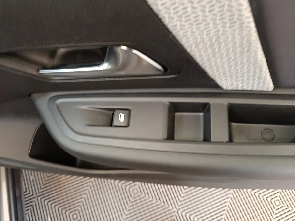 Détail de la porte côté conducteur d'une Citroën C4 gris clair, avec commande de lève-vitre et poignée intérieure.