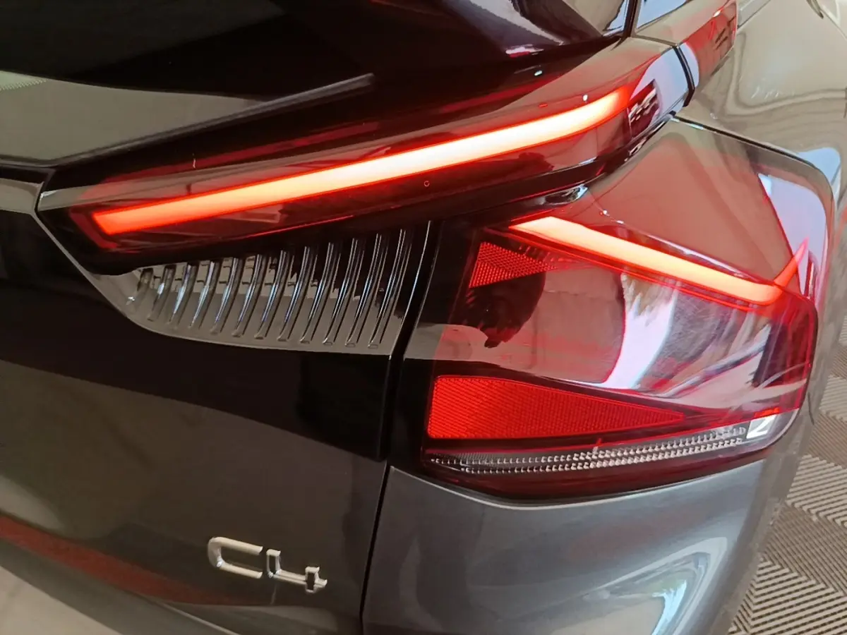 Gros plan sur le feu arrière droit rouge allumé d'une Citroën C4 gris clair, avec logo C4 visible sur la carrosserie.