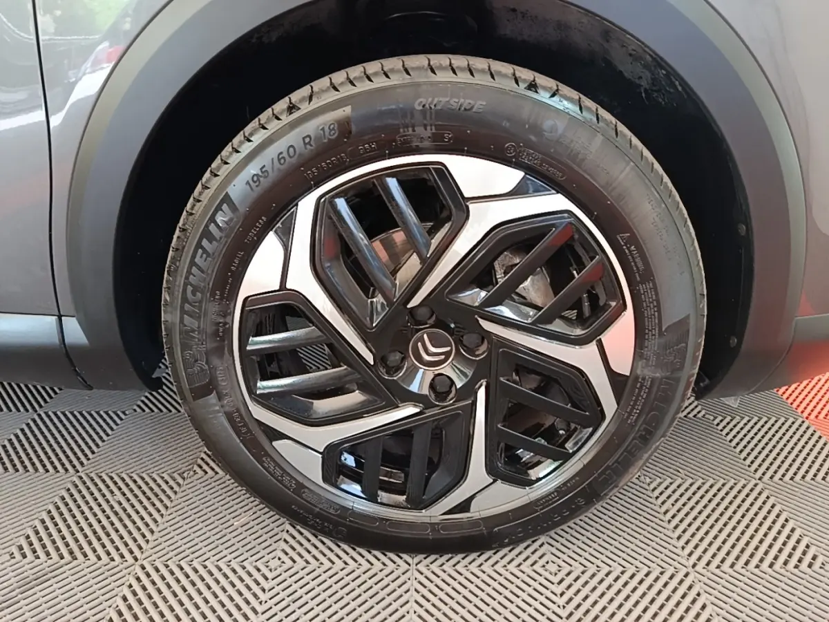 Gros plan sur la roue avant droite d’une Citroën C4 gris clair, avec jante alliage noire et argentée au design géométrique.