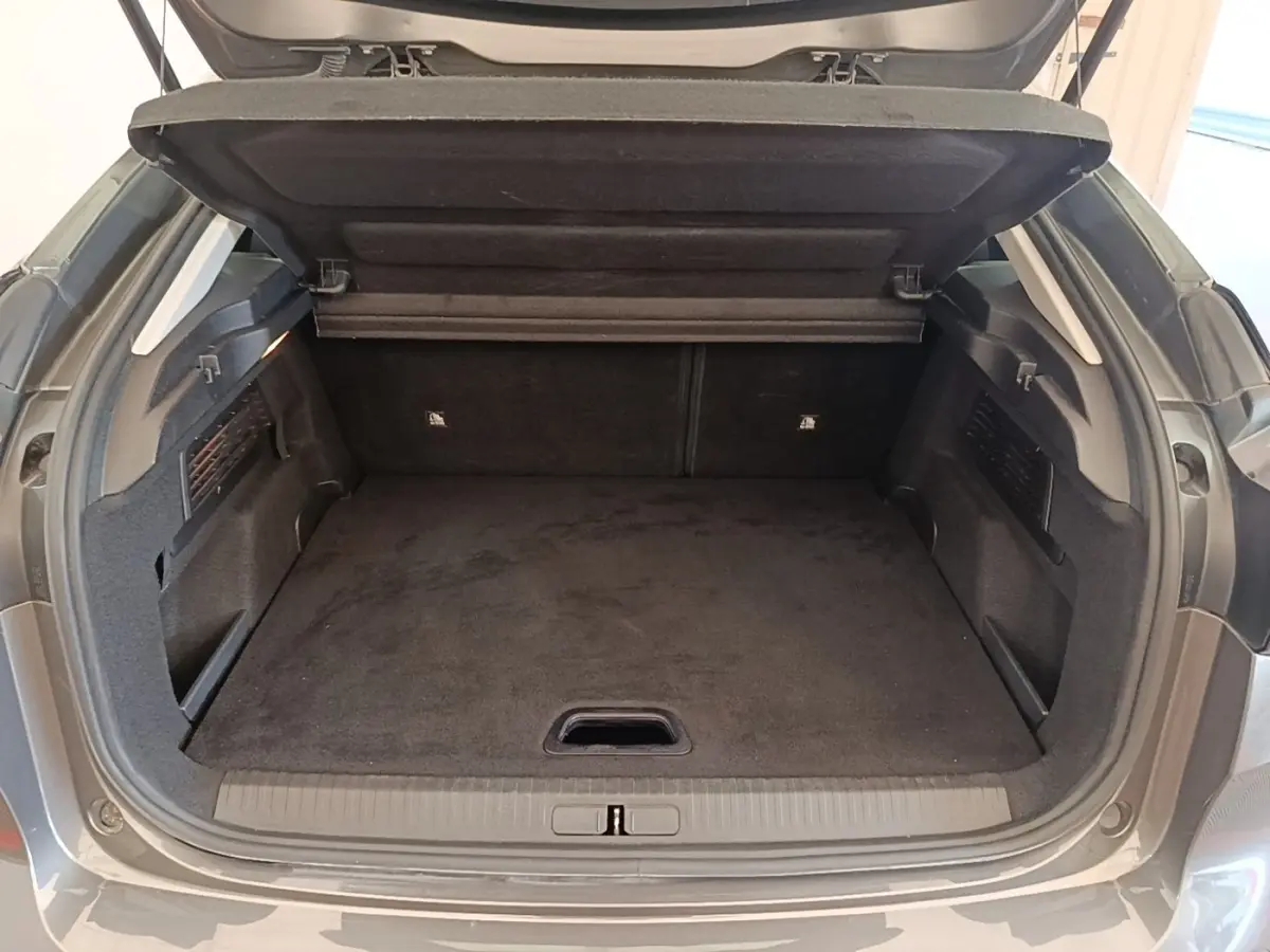 Coffre ouvert vu de l'arrière d'une Citroën C4 gris clair, montrant un espace de chargement propre et spacieux.
