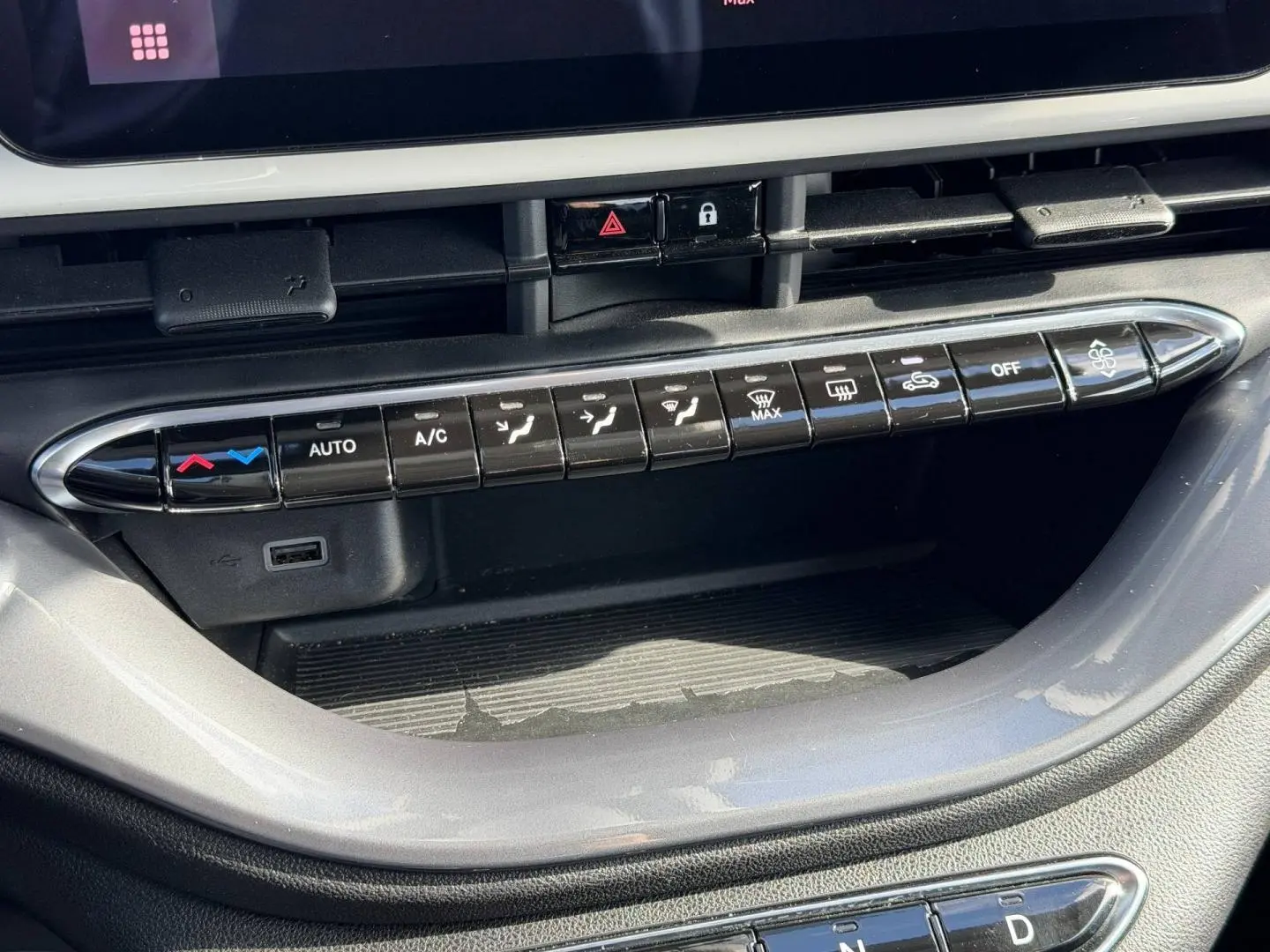 Gros plan sur la console centrale de la Fiat 500 e 118ch MY24 Ice White pastel, montrant les commandes de climatisation et un port USB.