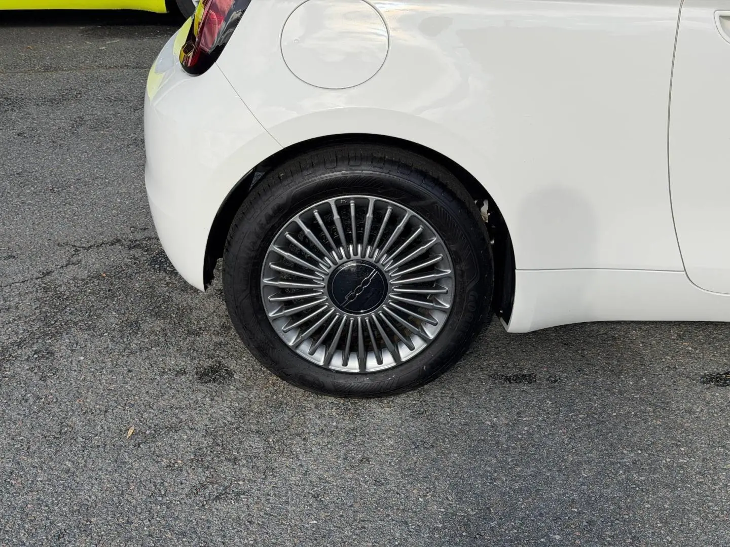 Gros plan sur la roue arrière droite d'une Fiat 500 e 118ch MY24 Ice White pastel avec jante à rayons fins.