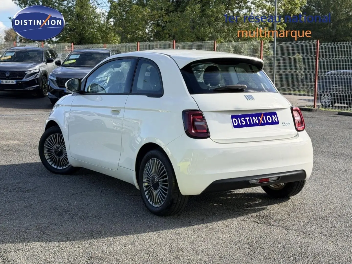 Vue 3/4 arrière droite de la Fiat 500 électrique 2024 en Ice White pastel avec jantes spécifiques et becquet noir.