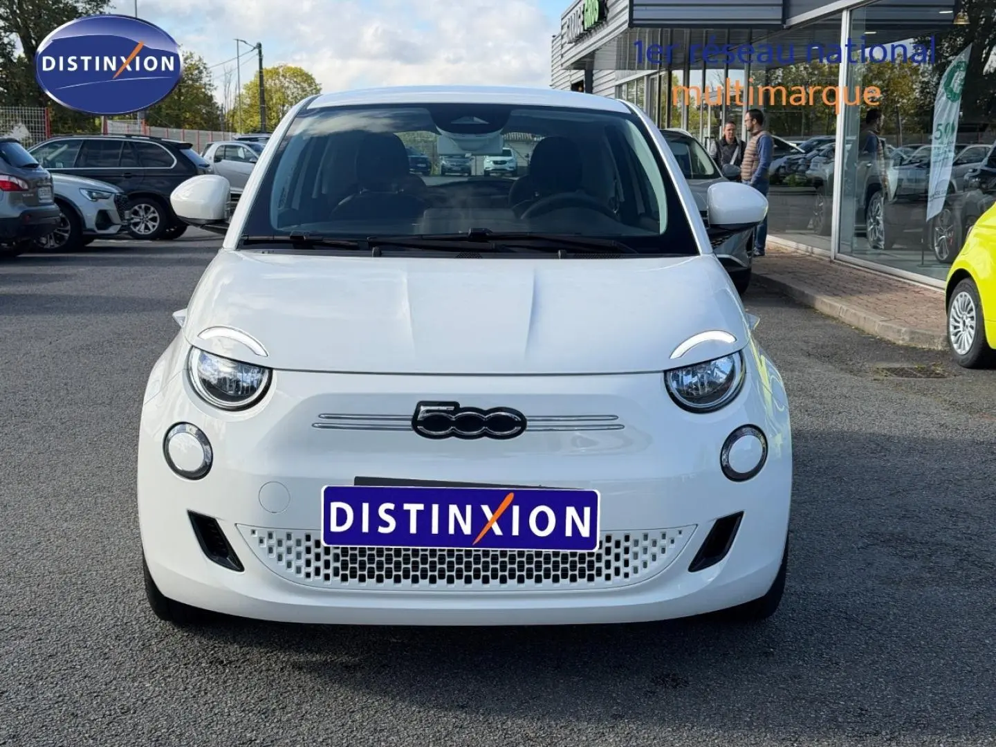Vue avant d'une FIAT 500 électrique 2024 en Ice White pastel, avec logo distinctif et calandre ajourée basse.