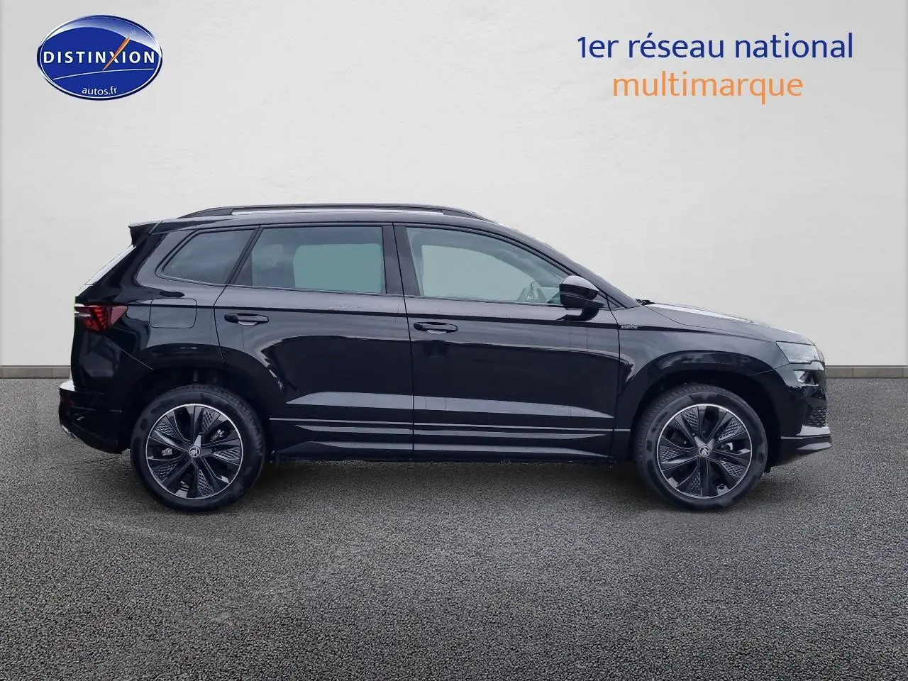 Profil droit d'un Skoda Karoq noir 2025 avec jantes alu et barres de toit sur fond neutre.