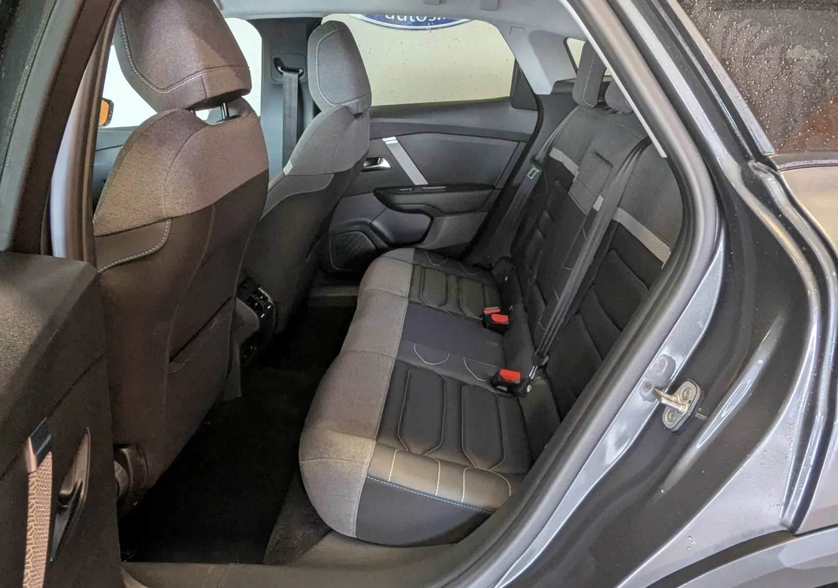 Vue intérieure côté arrière droit de la banquette arrière gris noir d'une Citroën C4 2024 gris platinium avec sellerie TEP/tissu.