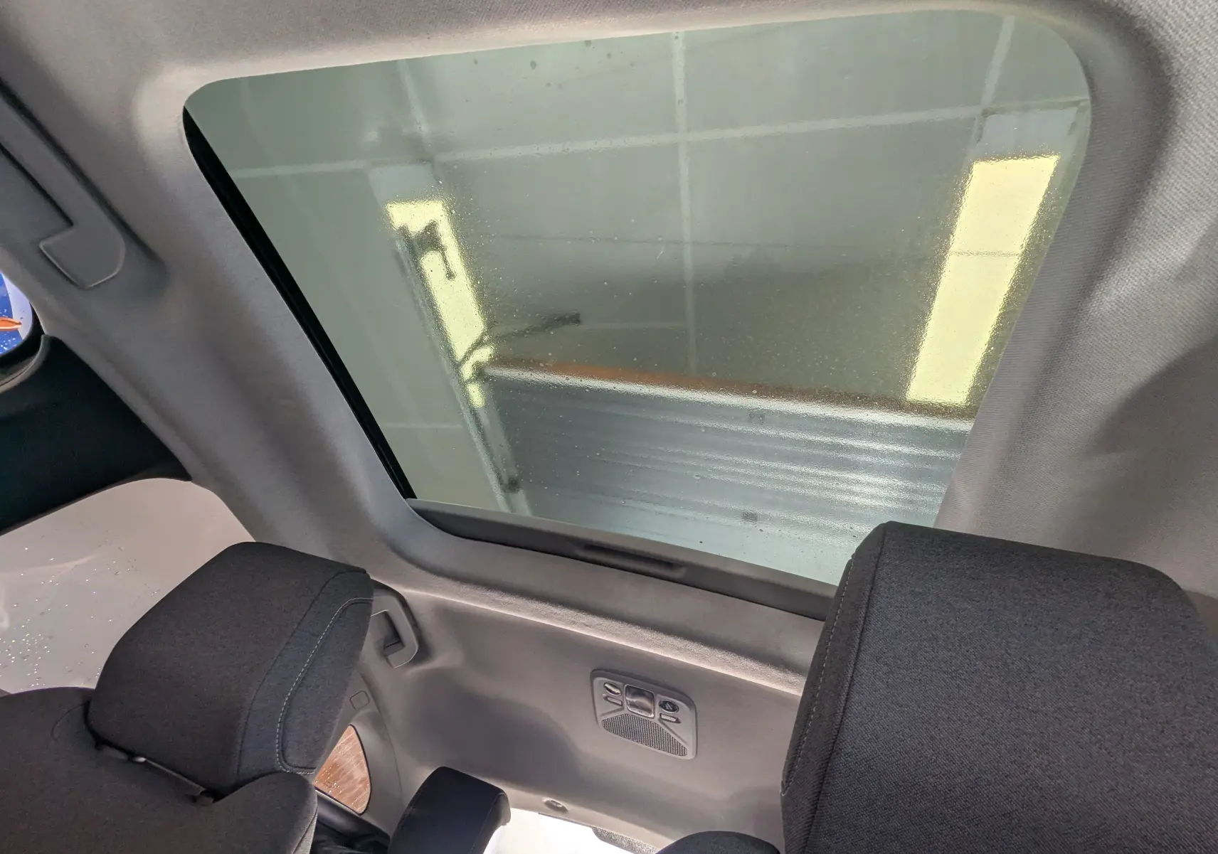 Vue intérieure du toit panoramique du Citroën C4 gris platinium 2024, avec appuie-têtes noirs et lumière ambiante.