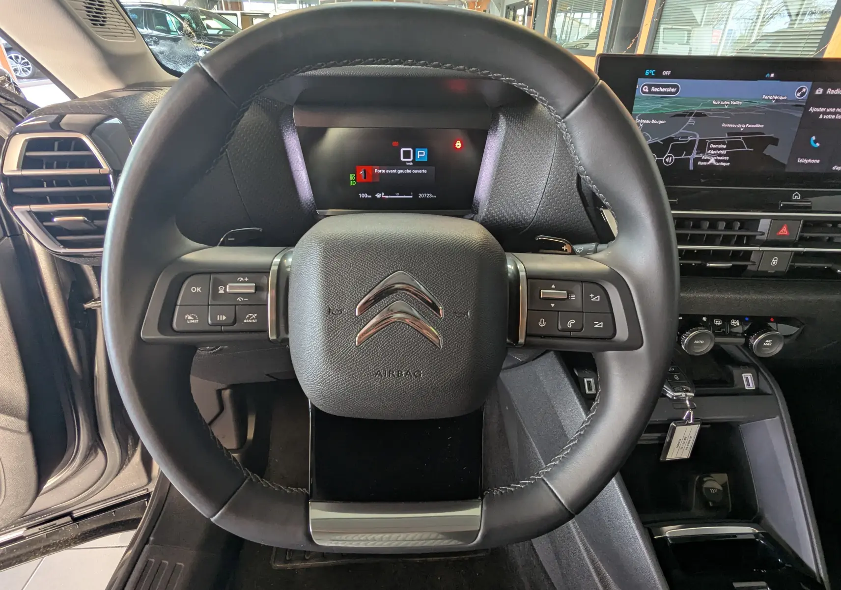 Vue centrée sur le volant noir du Citroën C4 2024 avec tableau de bord numérique et écran tactile GPS.