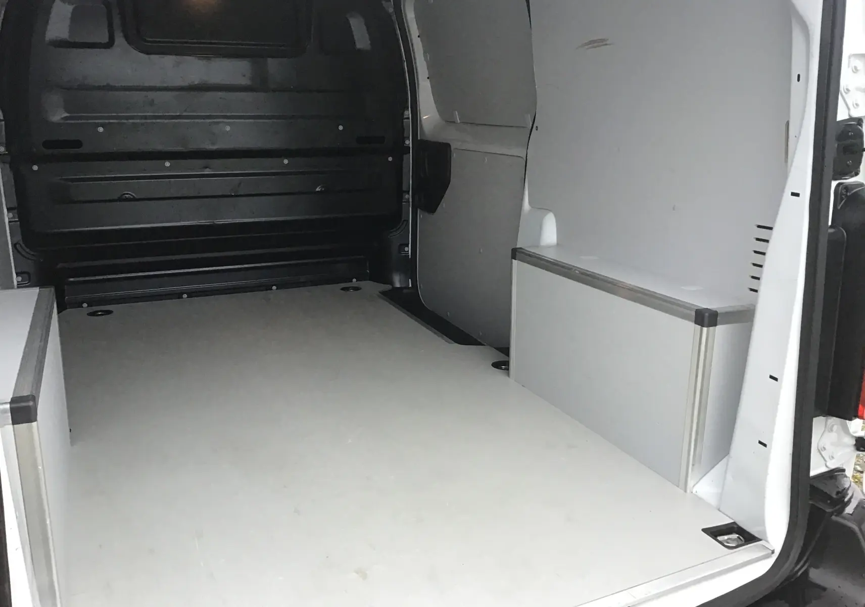 Vue intérieure arrière du fourgon FIAT Scudo blanc, montrant l'espace de chargement avec aménagements latéraux en bois clair.