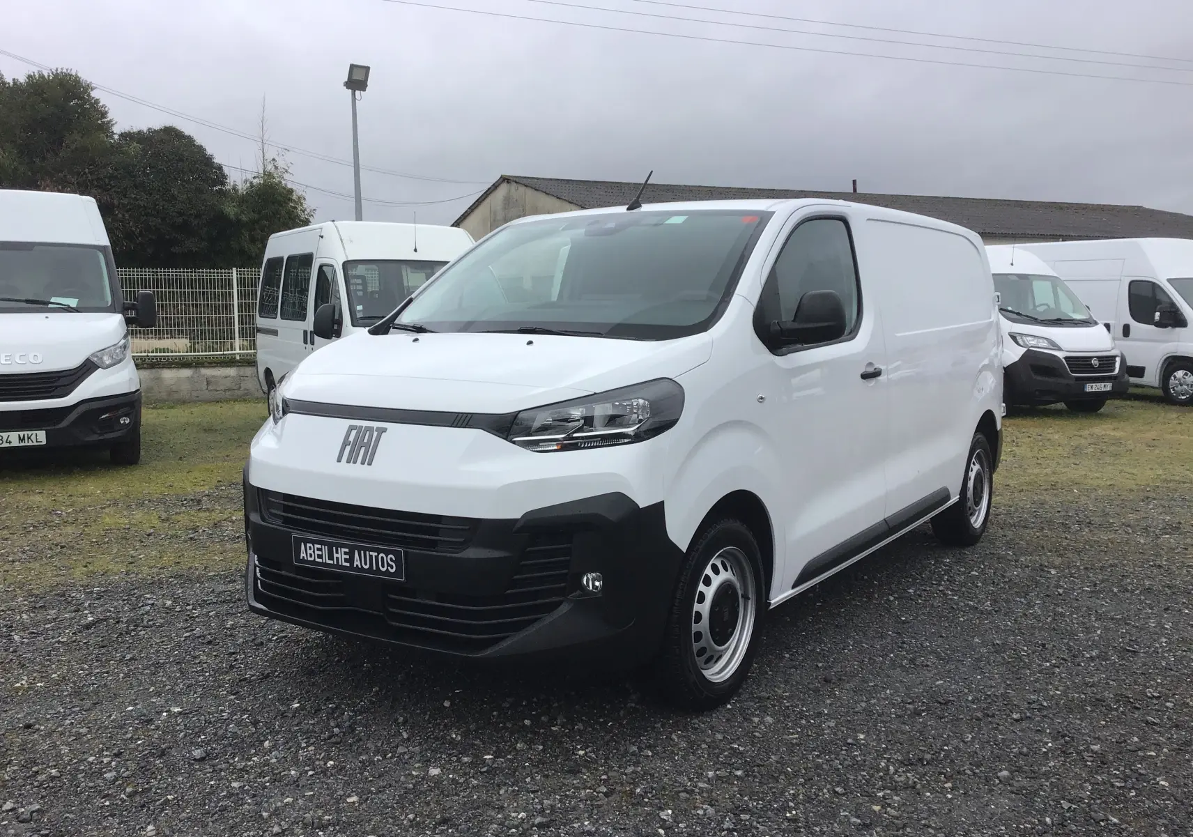 Vue 3/4 avant droite du FIAT Scudo Fourgon blanc 2024 avec pare-chocs noir et plaque de protection tôlée visible.