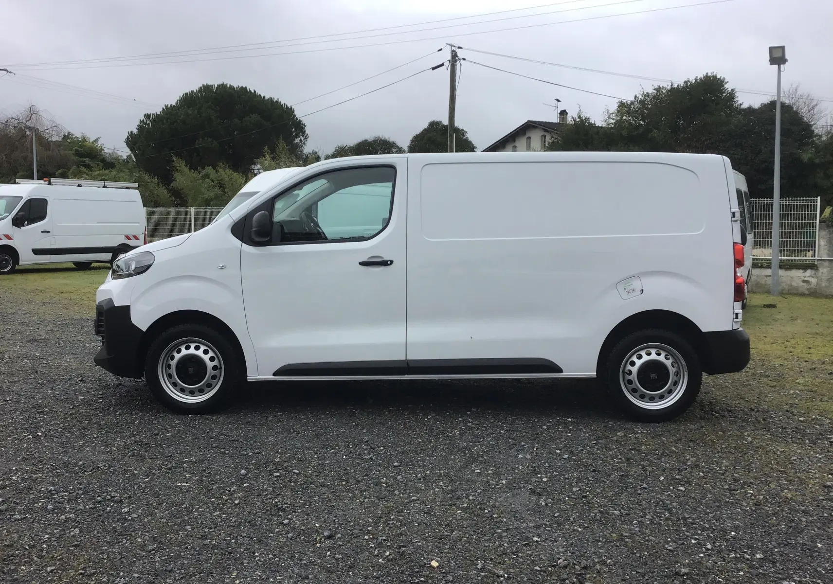 Vue de profil côté gauche d’un FIAT Scudo Fourgon blanc 2024 avec garde au sol réhaussée et jantes acier.