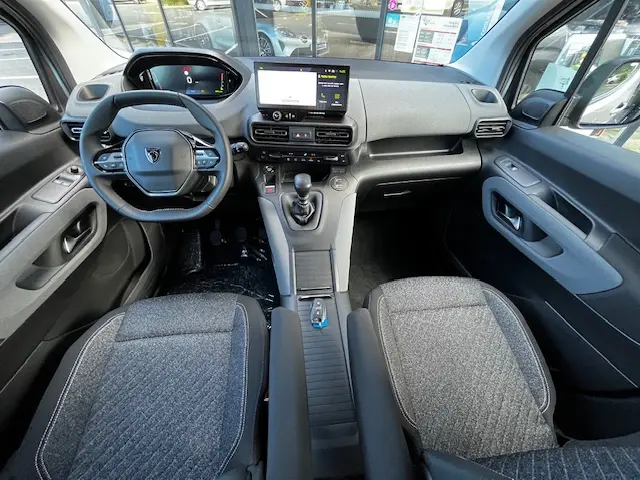 Vue intérieure avant du Peugeot Rifter 2024 gris foncé, montrant tableau de bord digital et volant multifonctions.
