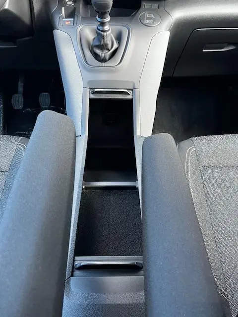 Vue rapprochée de la console centrale grise du Peugeot Rifter 2024 avec levier de vitesse manuel et accoudoirs noirs.