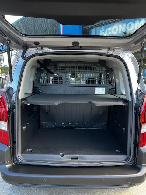 Vue arrière ouverte du Peugeot Rifter gris foncé 2024, montrant le coffre spacieux avec séparation métallique et tablette de rangement.