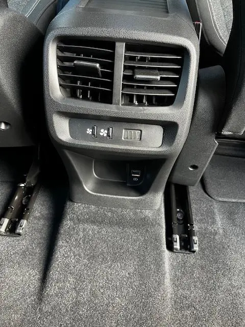 Vue rapprochée des aérateurs arrière et commandes de ventilation avec prise USB dans un Peugeot Rifter gris foncé 2024.