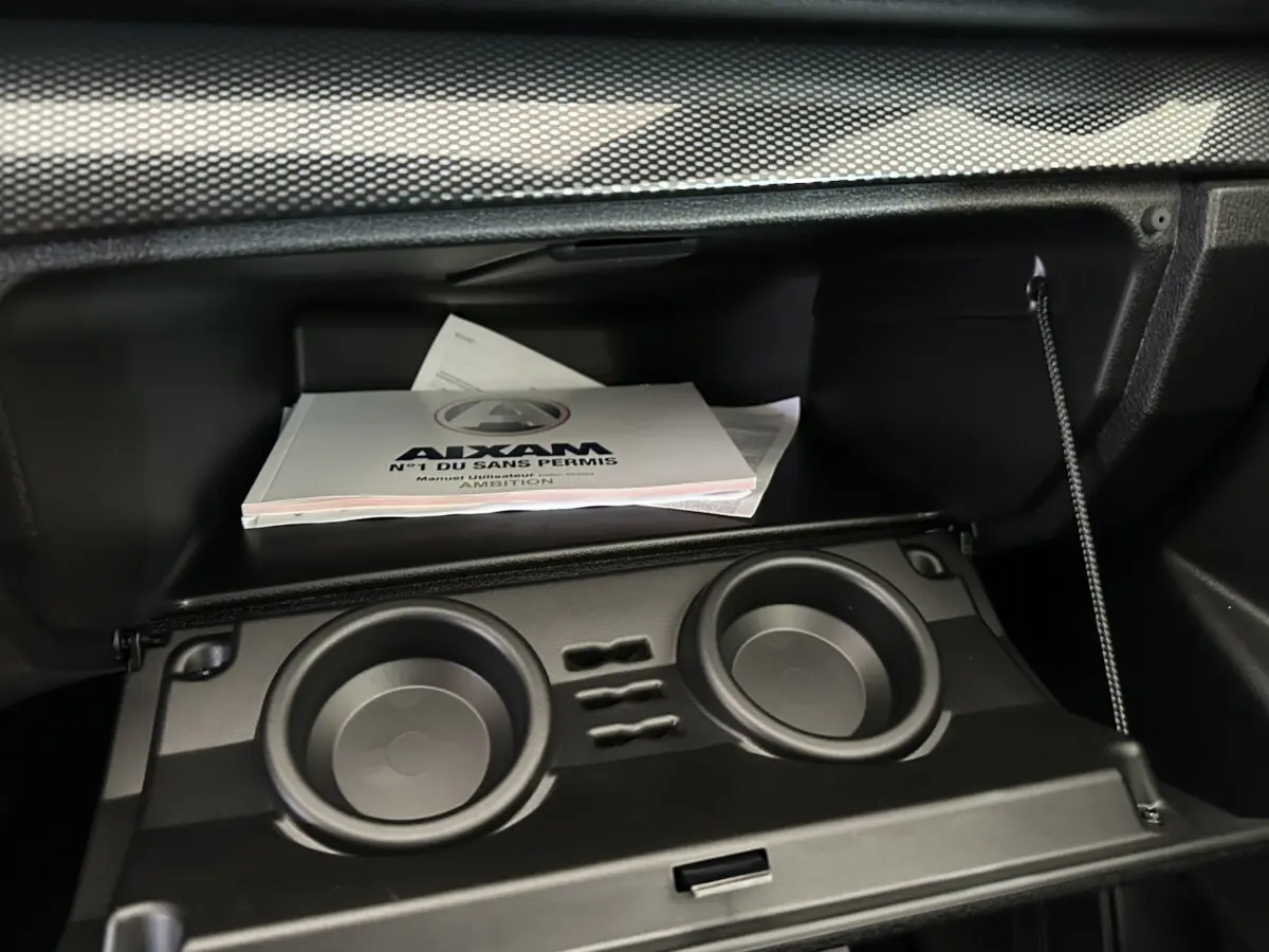 Intérieur de la boîte à gants de l'AIXAM AMBITION 0.5 City Coupe GTI avec manuel utilisateur visible.