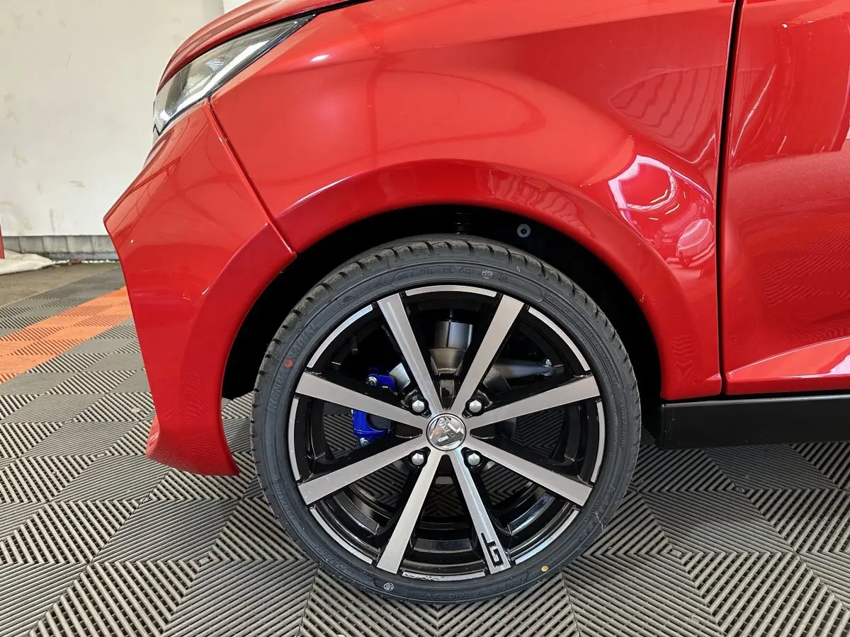 Gros plan sur la roue arrière droite rouge d'une Aixam Ambition 0.5 City Coupe GTI avec étrier de frein bleu.