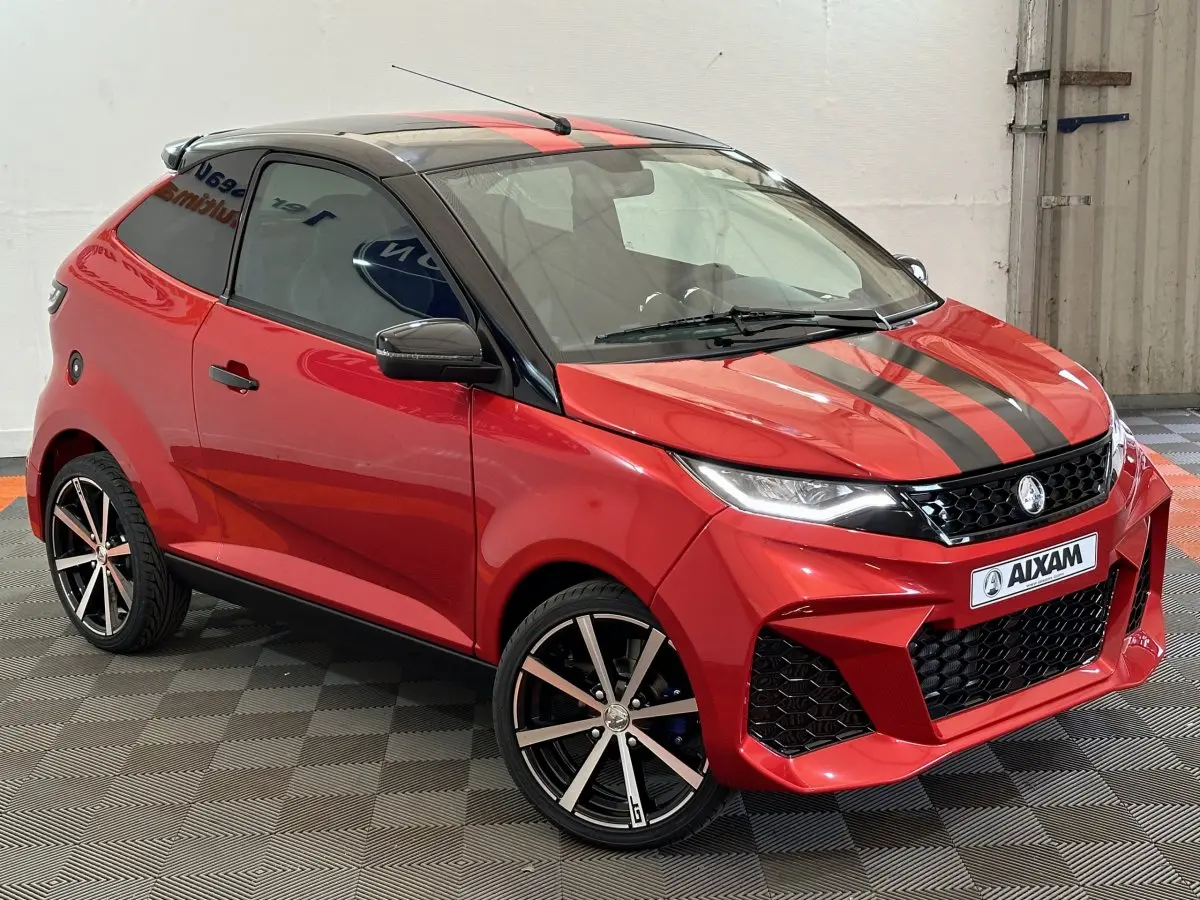 Vue 3/4 avant droite de l'AIXAM AMBITION rouge 2026 avec bandes noires sur capot et jantes alliage noires.