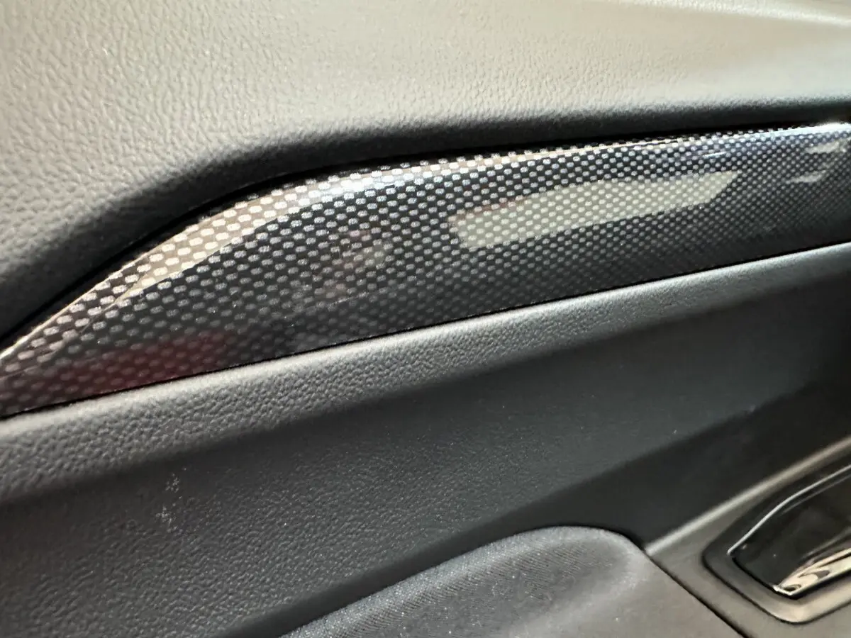 Détail intérieur montrant la garniture en carbone sur la porte côté conducteur de l'AIXAM AMBITION rouge 2026.